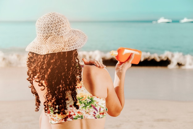 Vrouw die sunblock op strand toepast