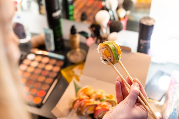 Vrouw die sushi-broodjes eet aan tafel - close-up foto. Traditionele Japanse Oosterse keuken met rauwe vis.