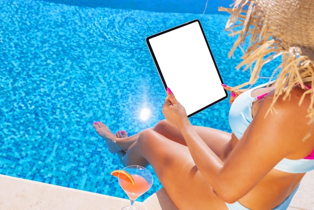 Vrouw die tablet gebruikt bij het verticale schermmodel bij het zwembad