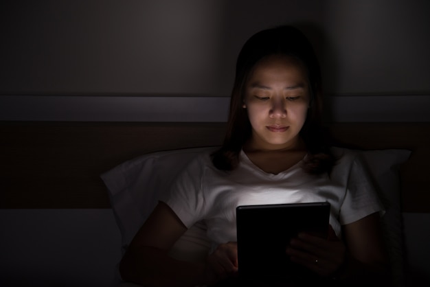 Vrouw die Tablet op bed gebruiken bij nacht