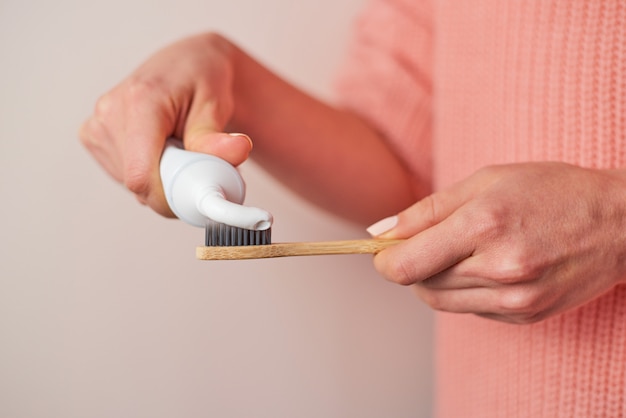 Vrouw die tandpasta op bamboe drukt