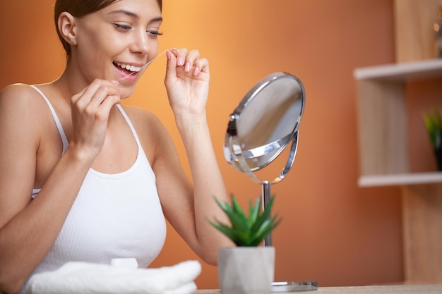 Vrouw die tandzijde gebruikt om haar tanden schoon te maken