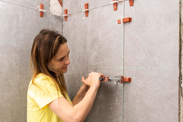 Foto vrouw die tegelnivelleringssysteem installeert bij de bouw of renovatie van een badkamer of keuken in een betegelde flat of huis