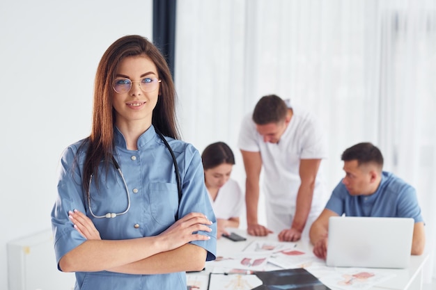 Vrouw die tegen een groep jonge artsen staat die samenwerkt in het moderne kantoor