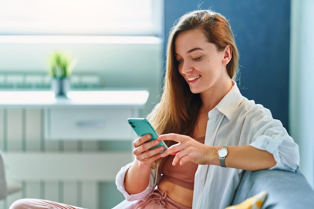 Vrouw die telefoon gebruikt terwijl ze op een bank rust