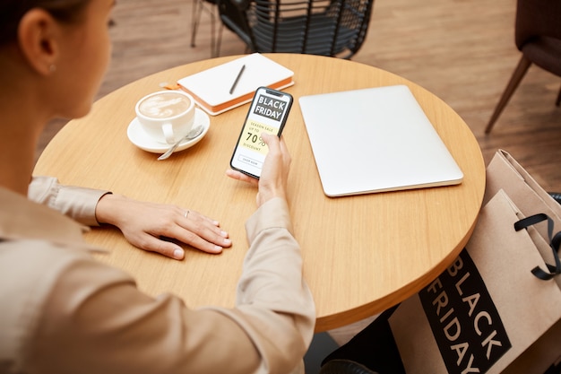 Vrouw die telefoon in koffie gebruiken