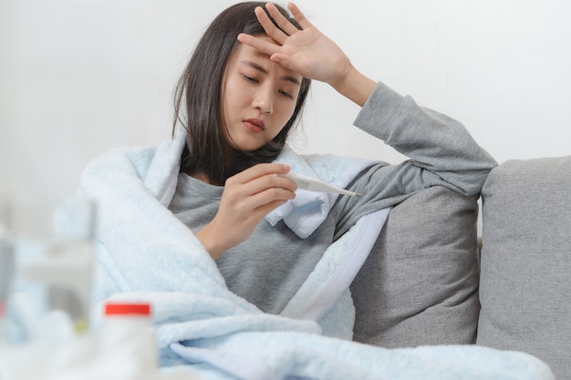 Vrouw die temperatuur meet haar lichaam op het bed. persoon kreeg koorts liggend op het bed.