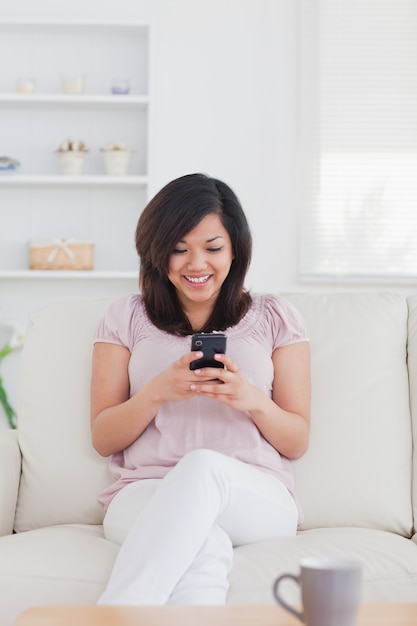 Vrouw die terwijl het houden van een telefoon glimlacht