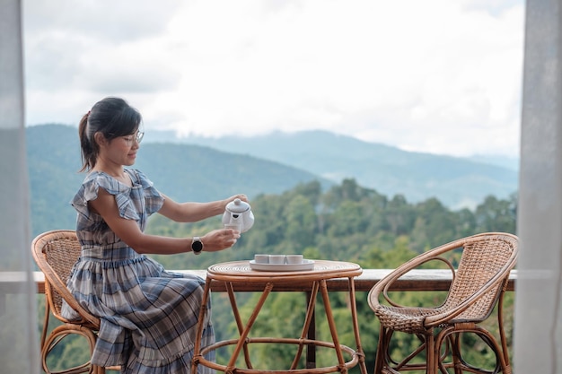 Vrouw die thee drinkt en kijkt naar de jonge blogger met uitzicht op de bergen, verblijft 's ochtends bij een homestay op het plattelandReizen vakantiereis en ontspannend concept