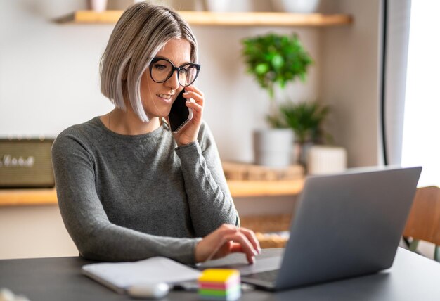 Foto vrouw die thuis aan het werken is en met haar mobiele telefoon praat