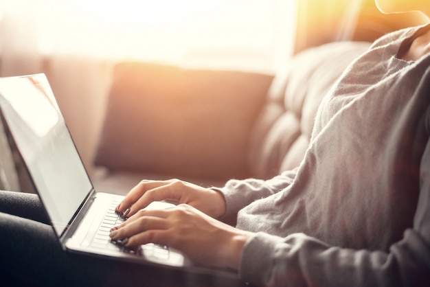 Vrouw die thuis bureauhand dicht uitwerken aan toetsenbord. een mooie vrouw zit thuis op een bank in een laptop en werkt vanuit huis. freelance concept