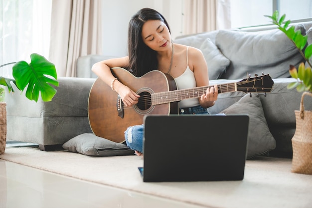 Vrouw die thuis een akoestische gitaarmuziekinstrument speelt, jonge Aziatische muzikant-meisjeslevensstijl