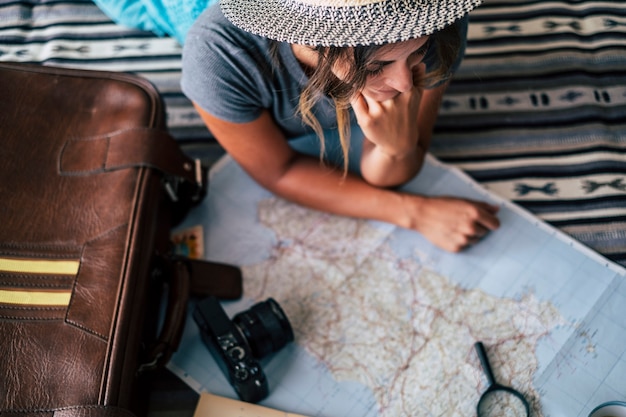 Foto vrouw die thuis een reisvakantie plant die de gidskaart en de glimlach kijkt