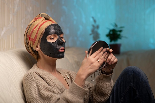 Vrouw die thuis een zwart gezichtsmasker van klei maakt