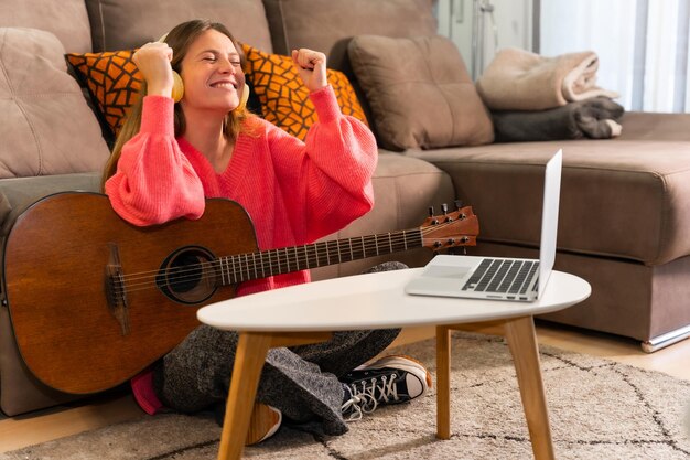 Vrouw die thuis gitaar leert spelen en viert dat ze het lied goed heeft gespeeld