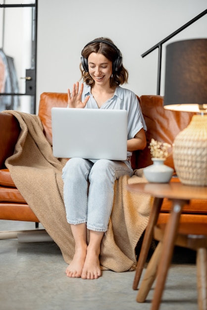 Vrouw die thuis met laptop en koptelefoon werkt