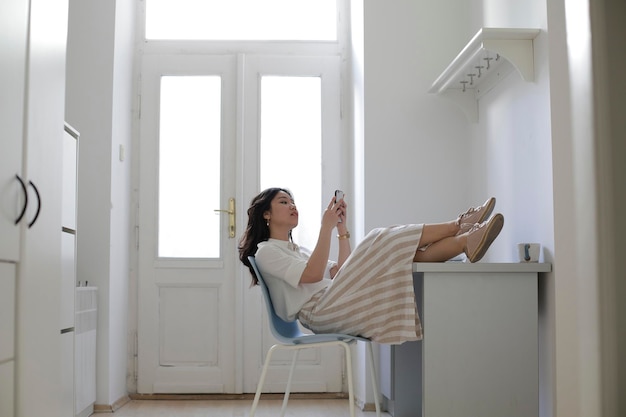 Foto vrouw die thuis op een stoel zit en een smartphone gebruikt