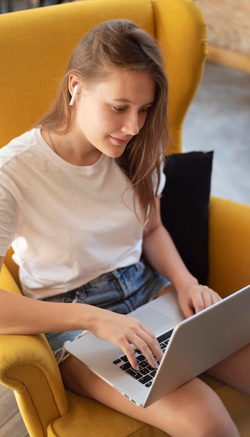 Vrouw die thuis op stoel met laptop werkt tijdens de pandemie