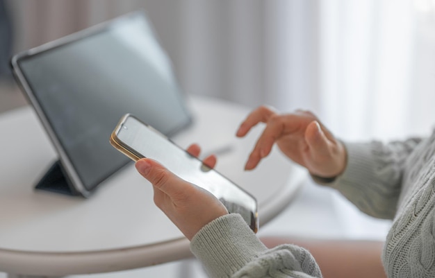 Vrouw die thuis werkt met tablet en telefoon Vrouwenhanden met mobiele telefoon Bijgesneden opname van vrouwenhanden met mobiele telefoon met contacten