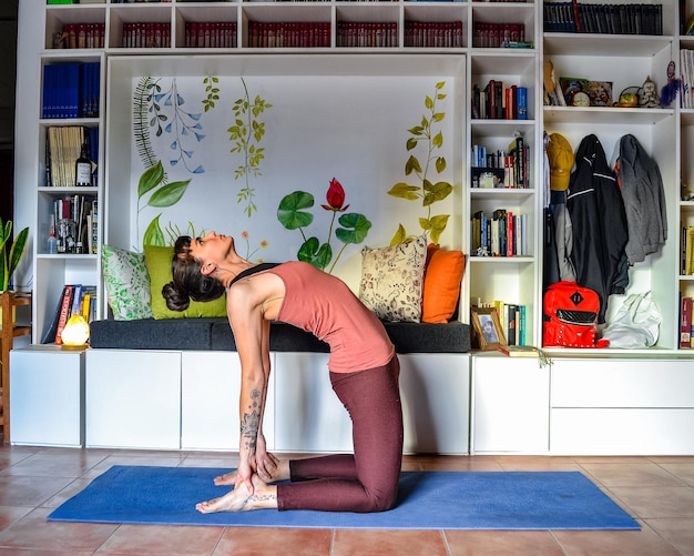 Foto vrouw die thuis yoga beoefent ustrasana houdingen