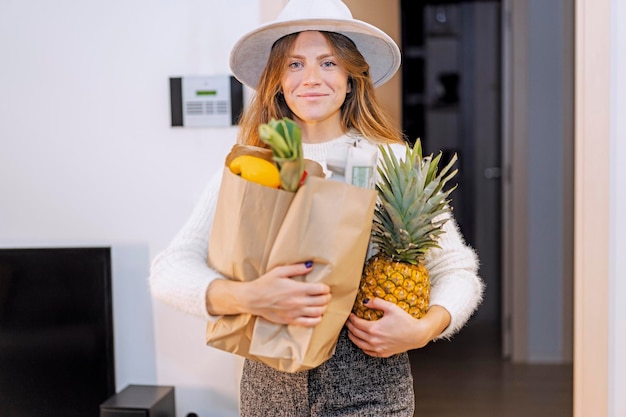 Vrouw die thuiskomt van de supermarkt met de aankoop van groenten en fruit