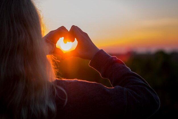 Foto vrouw die tijdens de zonsondergang op de weg tegen de hemel staat