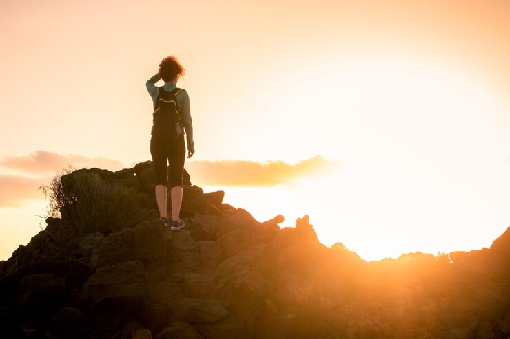 Foto vrouw die tijdens de zonsondergang op een rots tegen de hemel staat