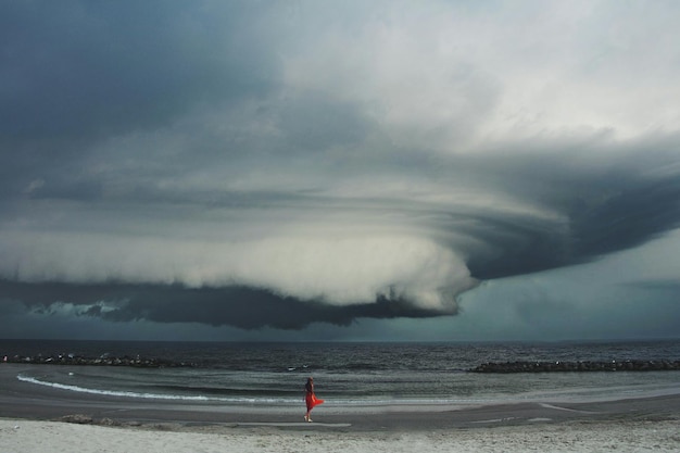 Foto vrouw die tijdens stormachtig weer aan wal staat