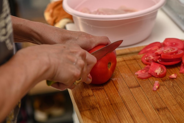 vrouw die tomaten snijdt op keukenplank 1