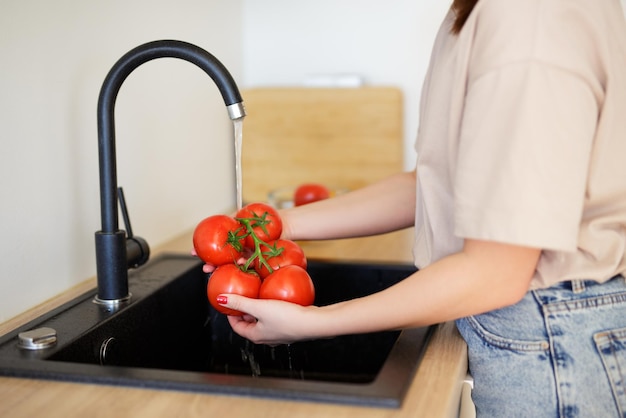 Vrouw die tomaten wast voor het koken