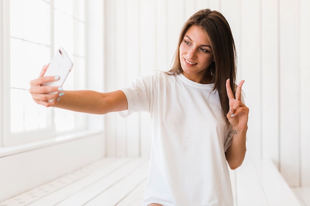 Foto vrouw die v-teken toont en selfie neemt