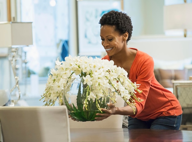 Vrouw die vaas met bloemen op tafel zet