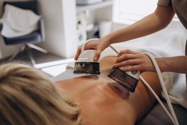 Foto vrouw die vacuümrolmassage op zijn rug ontvangt bij medisch schoonheidscentrum lymfedrainage massageprocedure