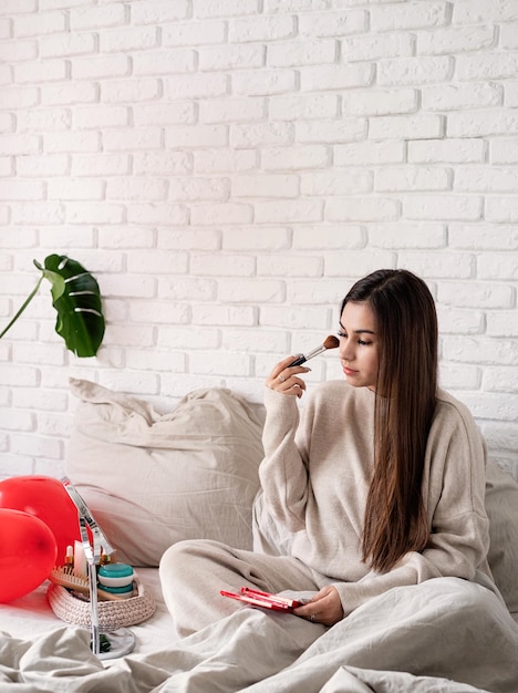 Vrouw die Valentijnsdag viert, zittend op het bed opmakend