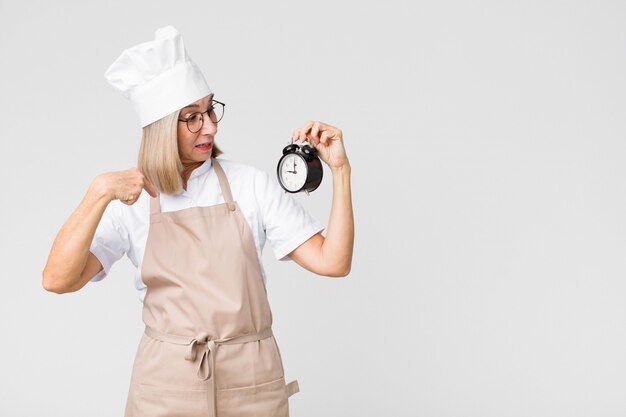 Vrouw die van de middelbare leeftijd de mooie bakker een wekker houdt