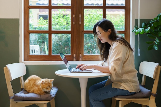 Vrouw die van huis met kat werkt kat in slaap op de laptop toetsenbord assistent kat die op Laptop werkt