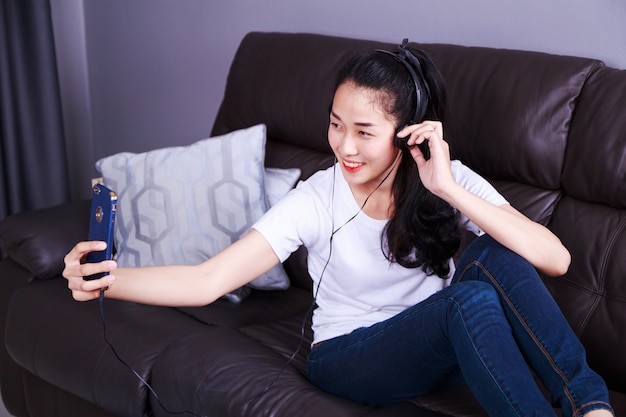 Vrouw die van muziek in hoofdtelefoons genieten, die selfie foto met cellphone maken terwijl het liggen op bank