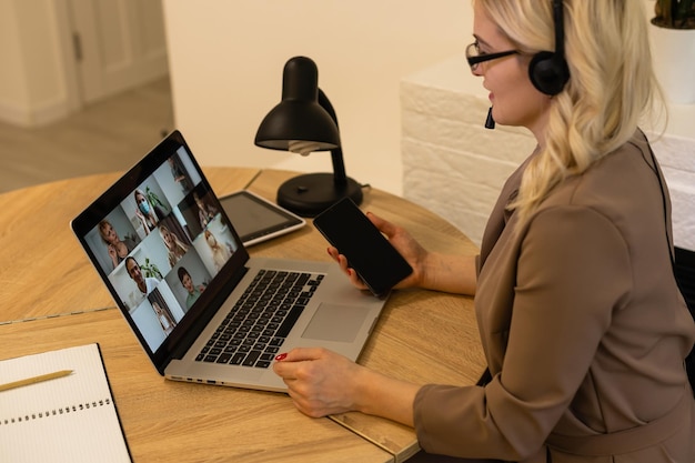 Vrouw die vanuit huis werkt met groepsvideoconferentie op laptop