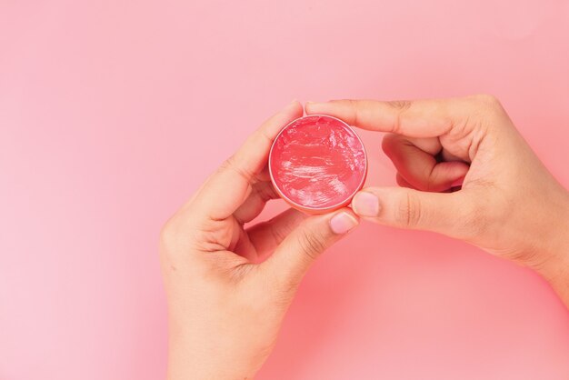 Vrouw die vaseline op huid op roze achtergrond gebruikt