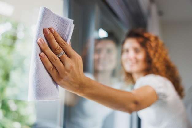 Foto vrouw die vensterglas schoonmaakt