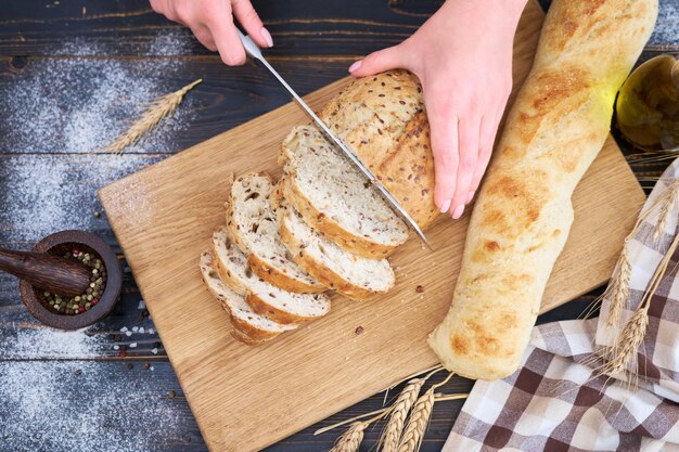 Vrouw die vers gebakken brood snijdt aan houten keukentafel