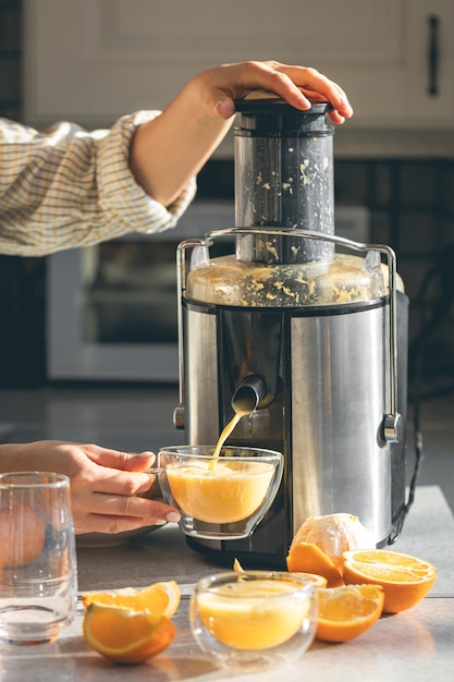 Vrouw die vers sinaasappelsap bereidt voor het ontbijt in de keuken