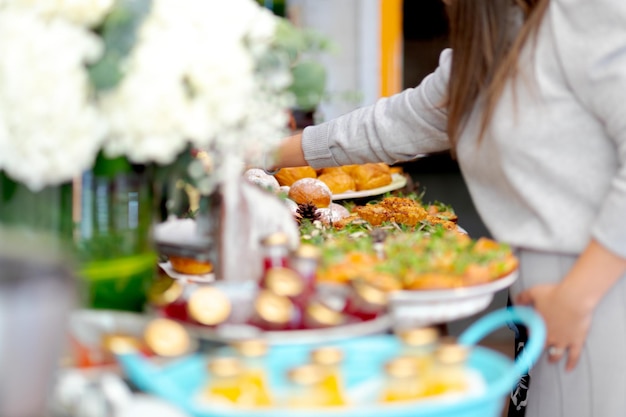 vrouw die verschillende snacks kiest, tafel met een verscheidenheid aan dienbladen met verschillende soorten snacks.