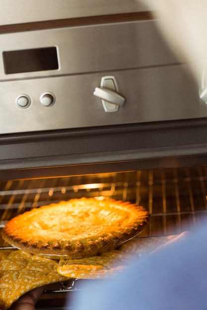 Foto vrouw die verse pastei neemt uit oven