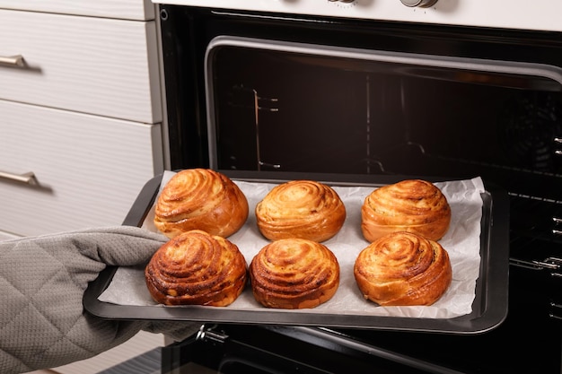 Vrouw die versgebakken broodjes uit ovenclose-up haalt