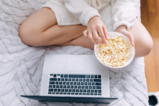 Vrouw die videogesprek voert en popcorn eet zittend op bed bovenaanzicht