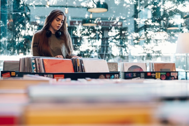 Foto vrouw die vinylverslag kiest in de winkel van het muziekverslag