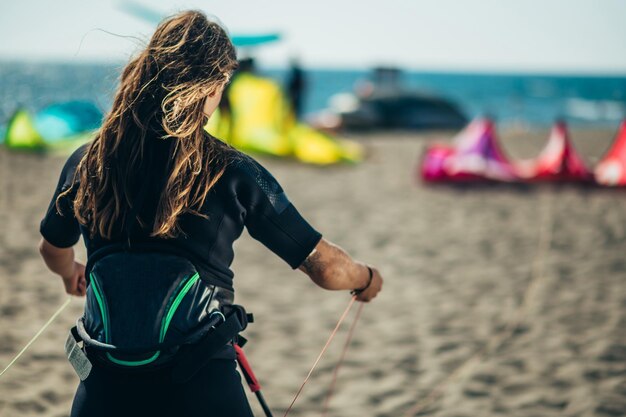 Vrouw die vlieglijnen en een stuurstang gebruikt om te kitesurfen