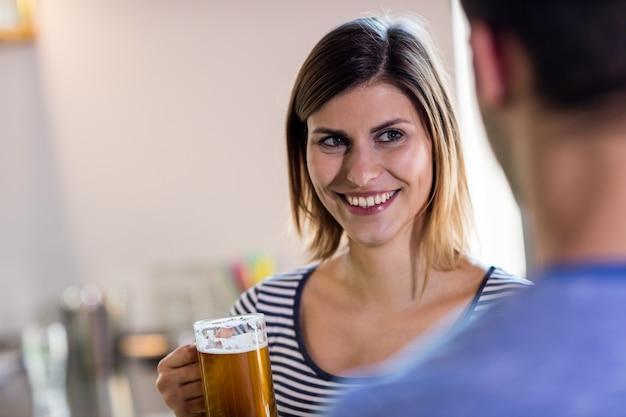 Vrouw die vriend bekijkt terwijl het drinken van bier