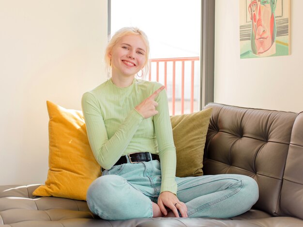 vrouw die vrolijk lacht, vrouw die zich gelukkig voelt en naar de zijkant en naar boven wijst, een object in de kopieerruimte toont